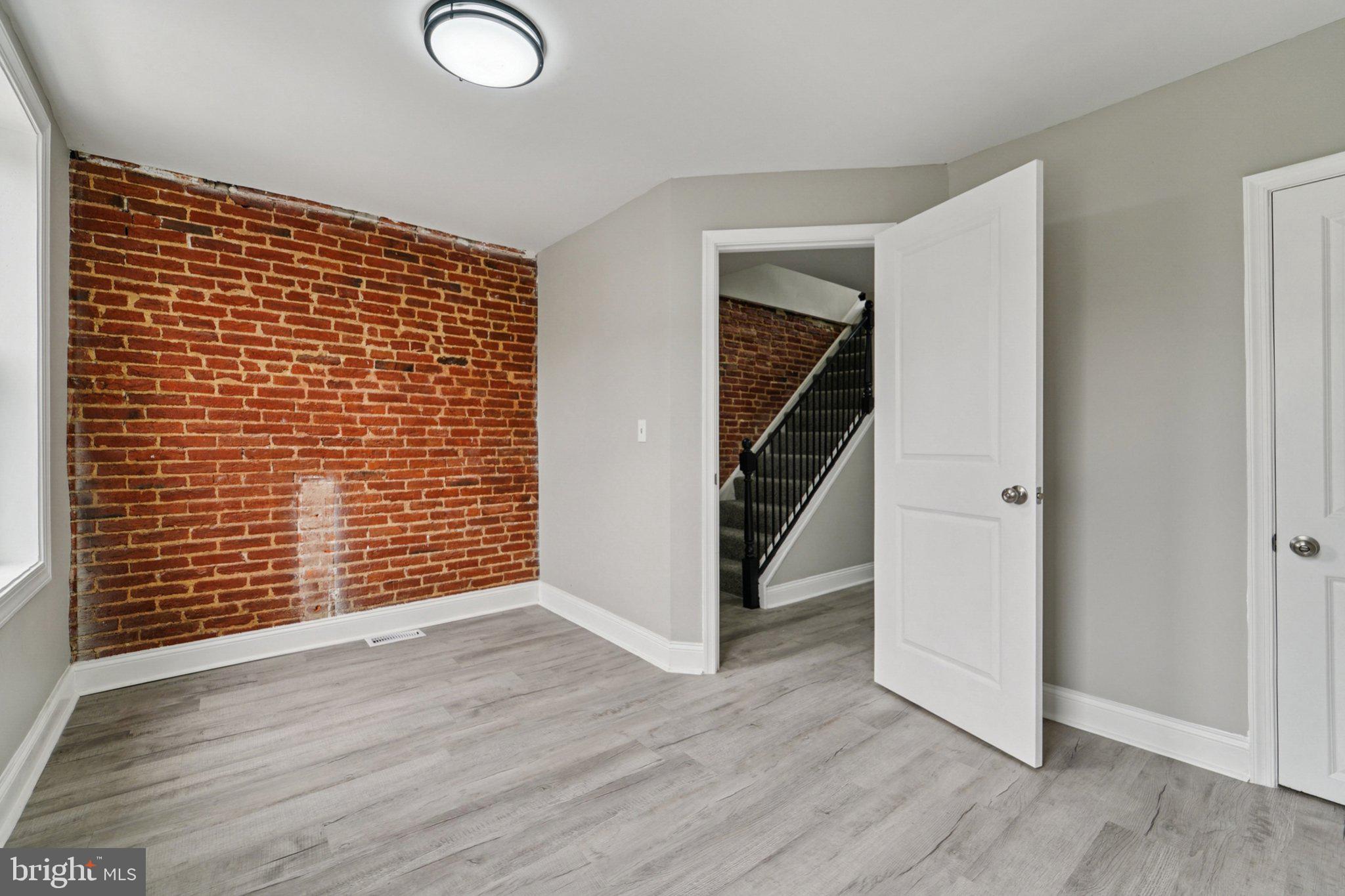 1525 West Pratt Street Baltimore, MD 21223 - Photo 15 of 31 an empty room with wooden floor and stairs