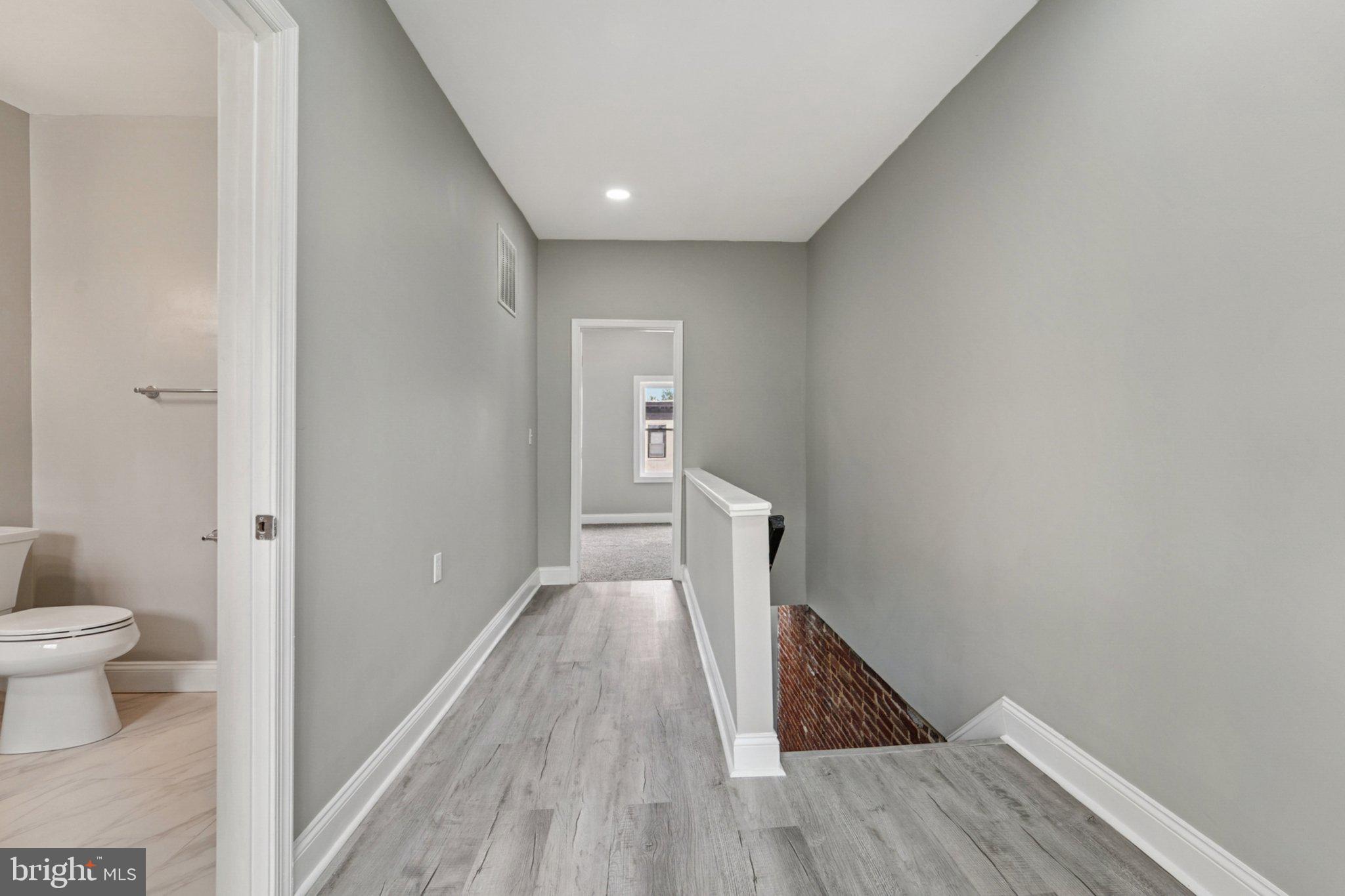 1525 West Pratt Street Baltimore, MD 21223 - Photo 16 of 31 a view of a hallway with wooden floor and a toilet