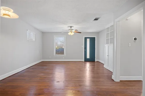 a view of an empty room with wooden floor and a window