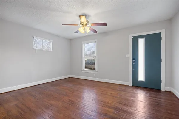 a view of an empty room with wooden floor and a window