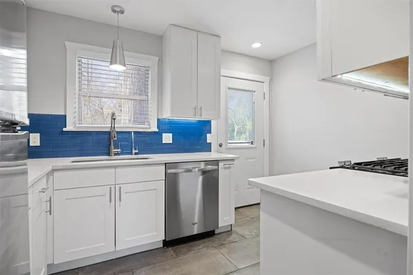 a kitchen with white cabinets and sink