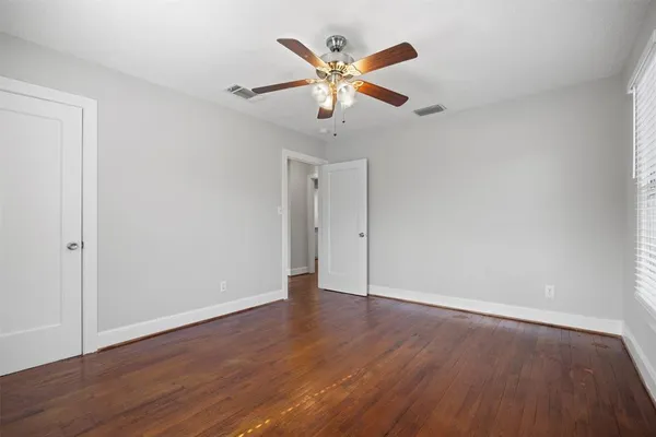 an empty room with wooden floor and ceiling fan