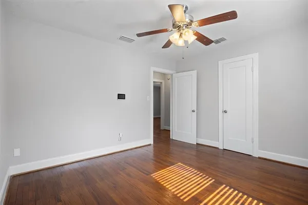 an empty room with wooden floor and a ceiling fan