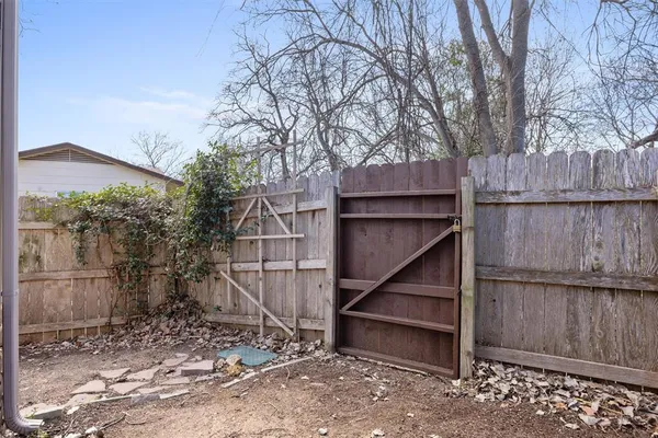 a view of backyard with wooden fence and large trees