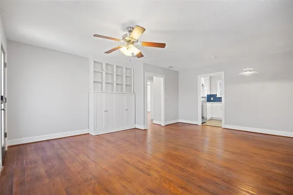 an empty room with wooden floor fan and windows