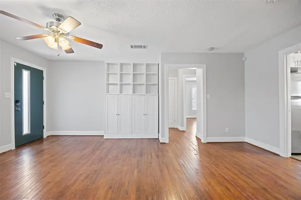 an empty room with wooden floor and chandelier fan