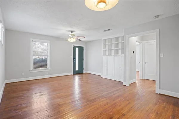 a view of an empty room with wooden floor and a window