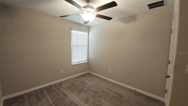 an empty room with a window and a fan