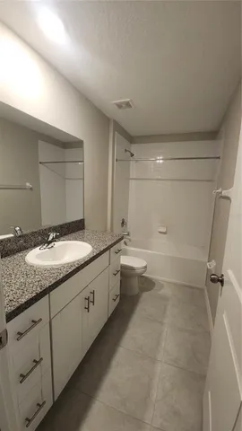 a bathroom with a granite countertop sink a toilet and bathtub