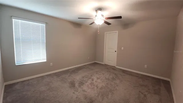 an empty room with a window and a fan