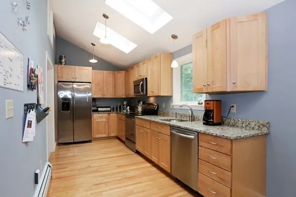 a kitchen with granite countertop a refrigerator oven a sink dishwasher and white cabinets with wooden floor