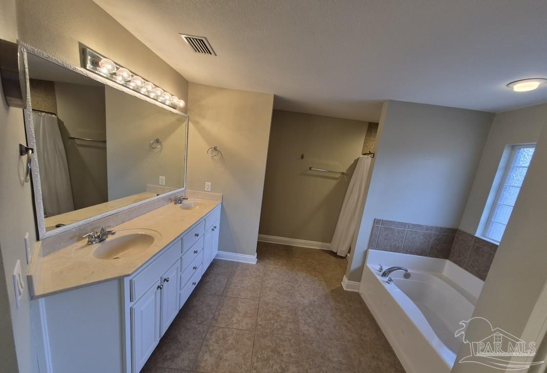 1960 Amhurst Court Navarre, FL 32566 - Photo 28 of 47 a spacious bathroom with a double vanity sink a mirror and a bathtub