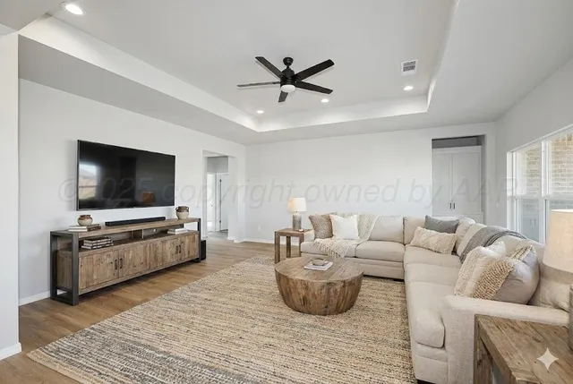 a view of an empty room and kitchen view with wooden floor