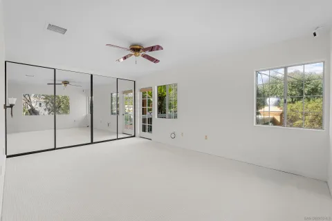 an empty room with windows and fan