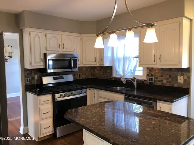 a kitchen with granite countertop a stove a sink and a microwave