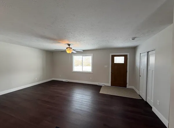 an empty room with wooden floor closet and windows
