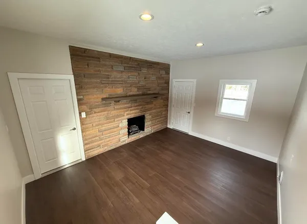 an empty room with wooden floor fireplace and windows
