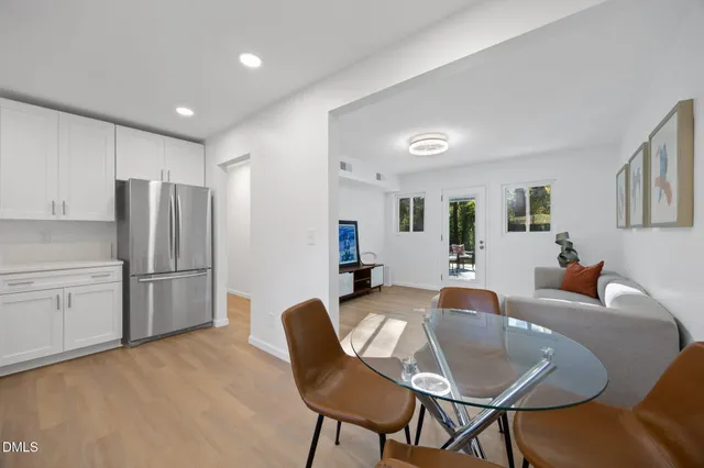 a kitchen with stainless steel appliances granite countertop a refrigerator a stove a sink dishwasher a dining table and chairs with wooden floor