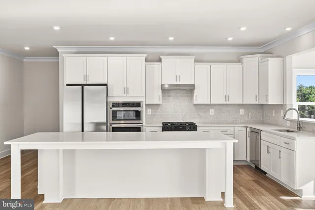 a kitchen with stainless steel appliances granite countertop a stove a sink and white cabinets