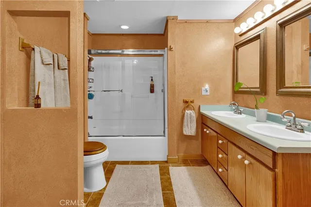 a bathroom with a double vanity sink toilet mirror and shower