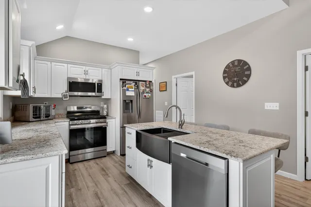 a kitchen with stainless steel appliances granite countertop a table chairs stove and sink