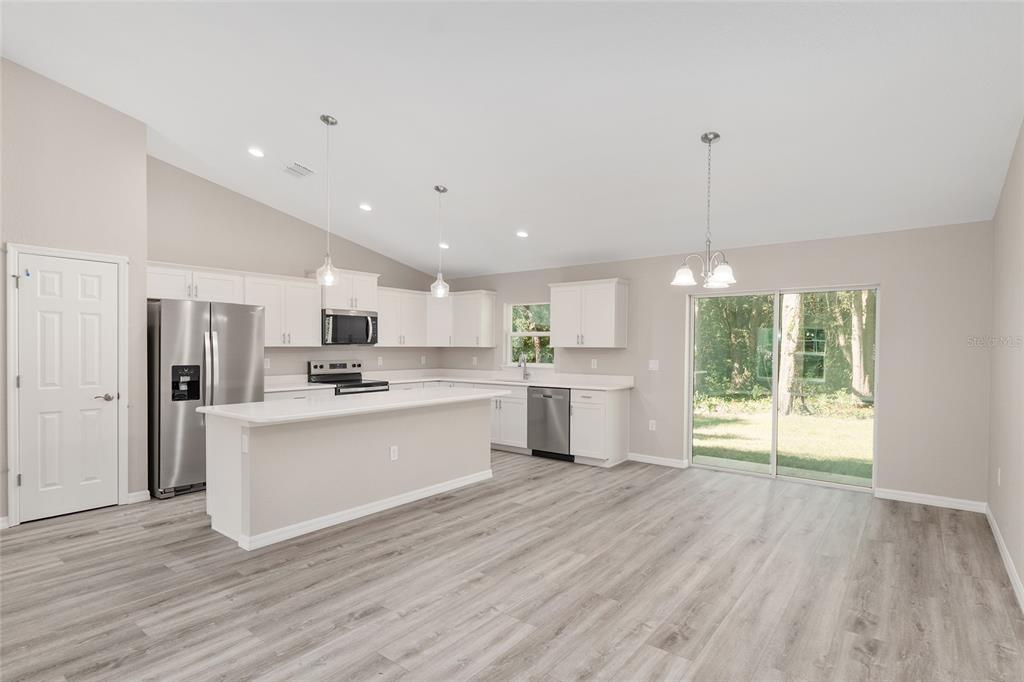 19230 Southwest 97th Street Dunnellon, FL 34432 - Photo 6 of 30 a large white kitchen with stainless steel appliances granite countertop a stove a sink dishwasher and a refrigerator with wooden floors