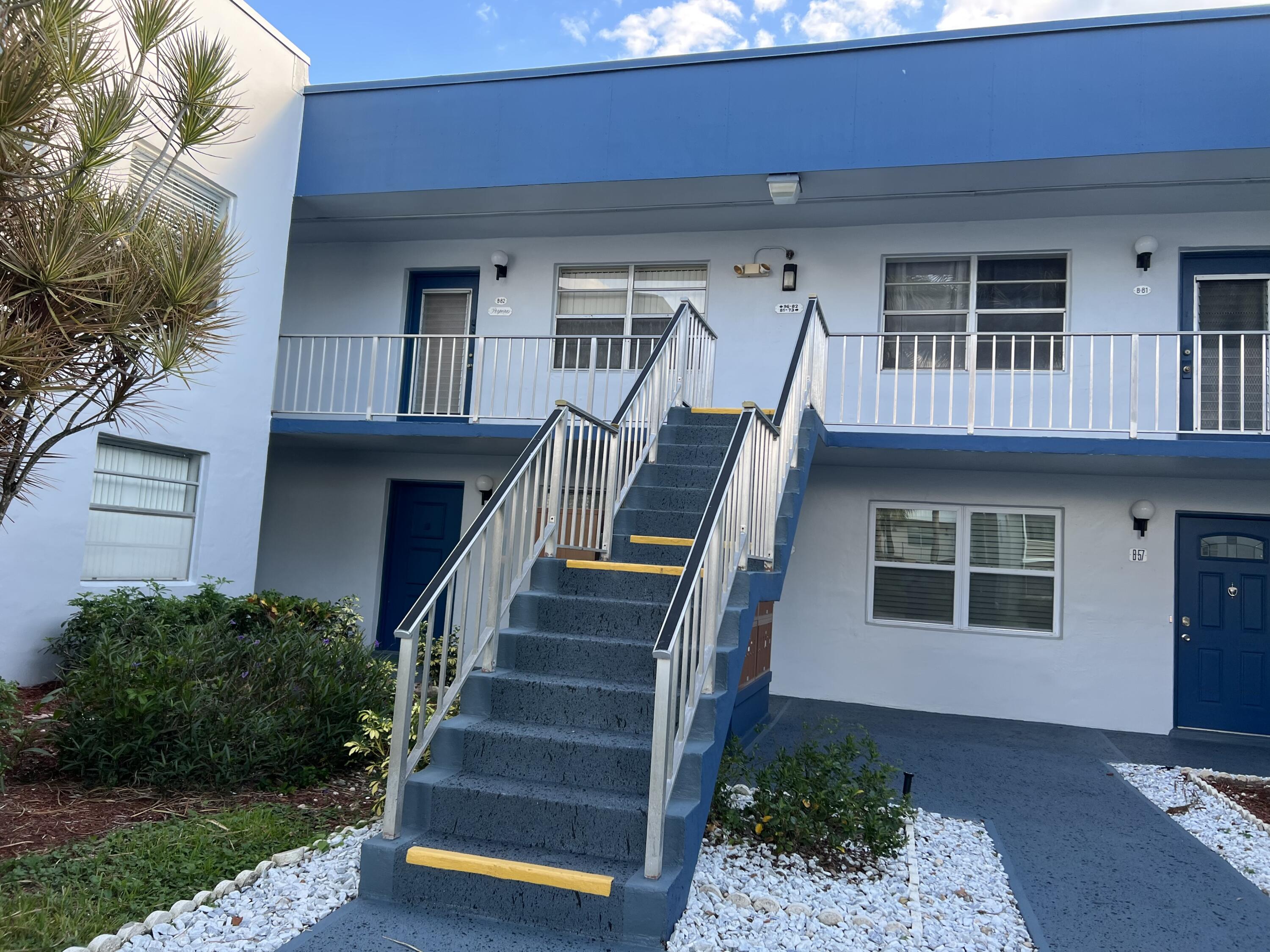 82 Normandy B Delray Beach, FL 33484 - Photo 28 of 31 a front view of a house with wooden stairs and a large tree