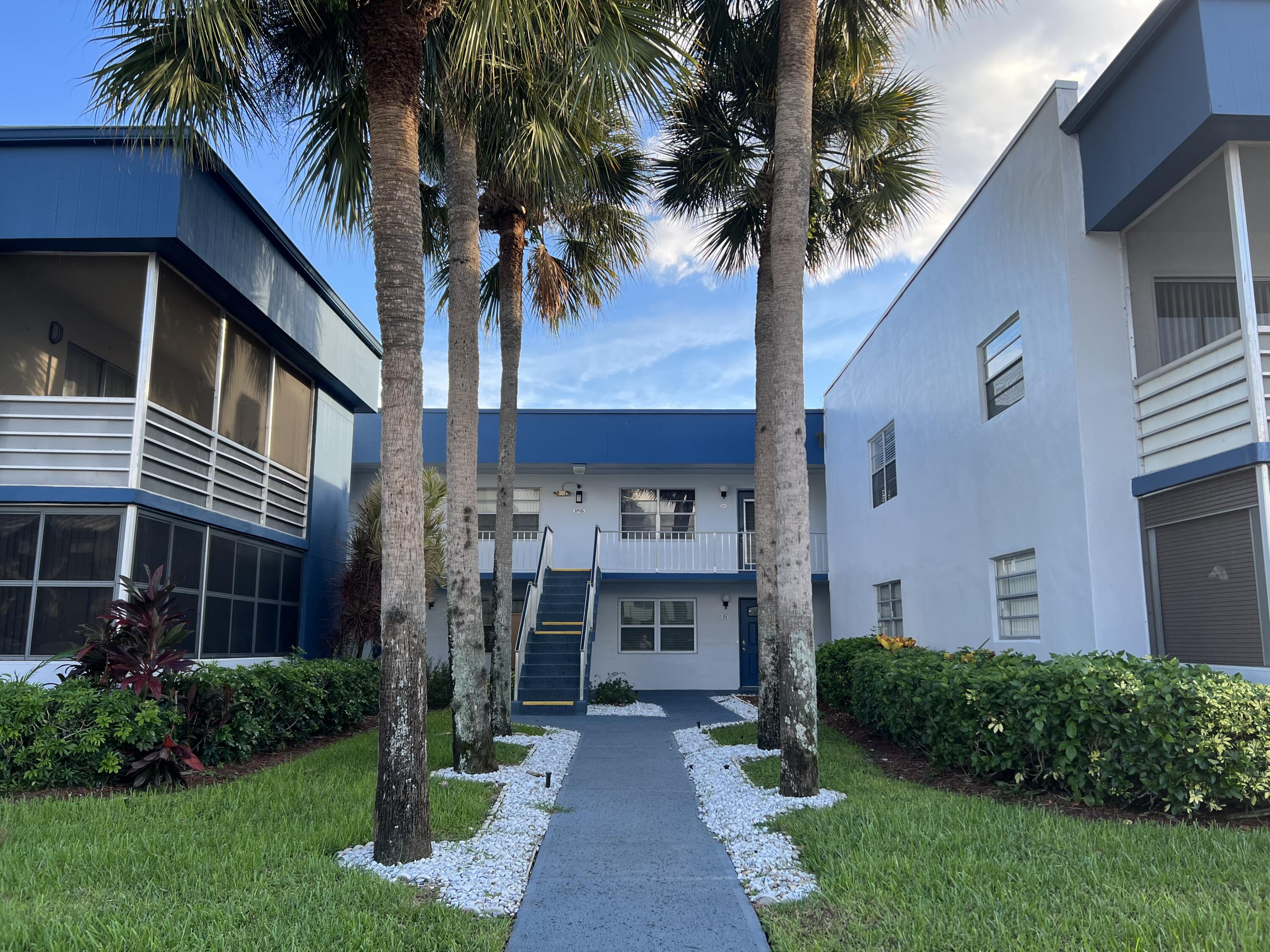 82 Normandy B Delray Beach, FL 33484 - Photo 29 of 31 a front view of a house with a yard and potted plants