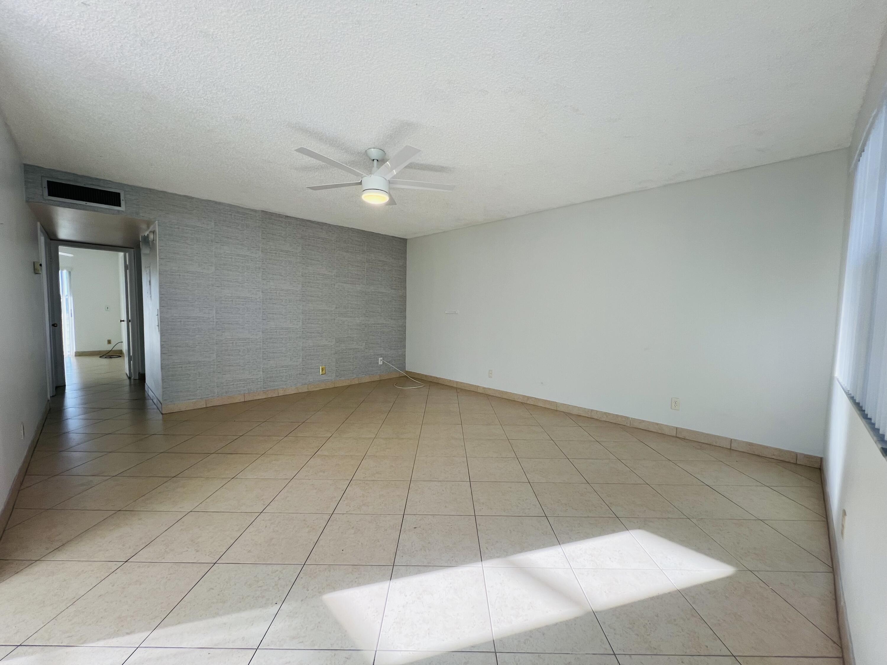 82 Normandy B Delray Beach, FL 33484 - Photo 8 of 31 an empty room with a ceiling fan and carpet