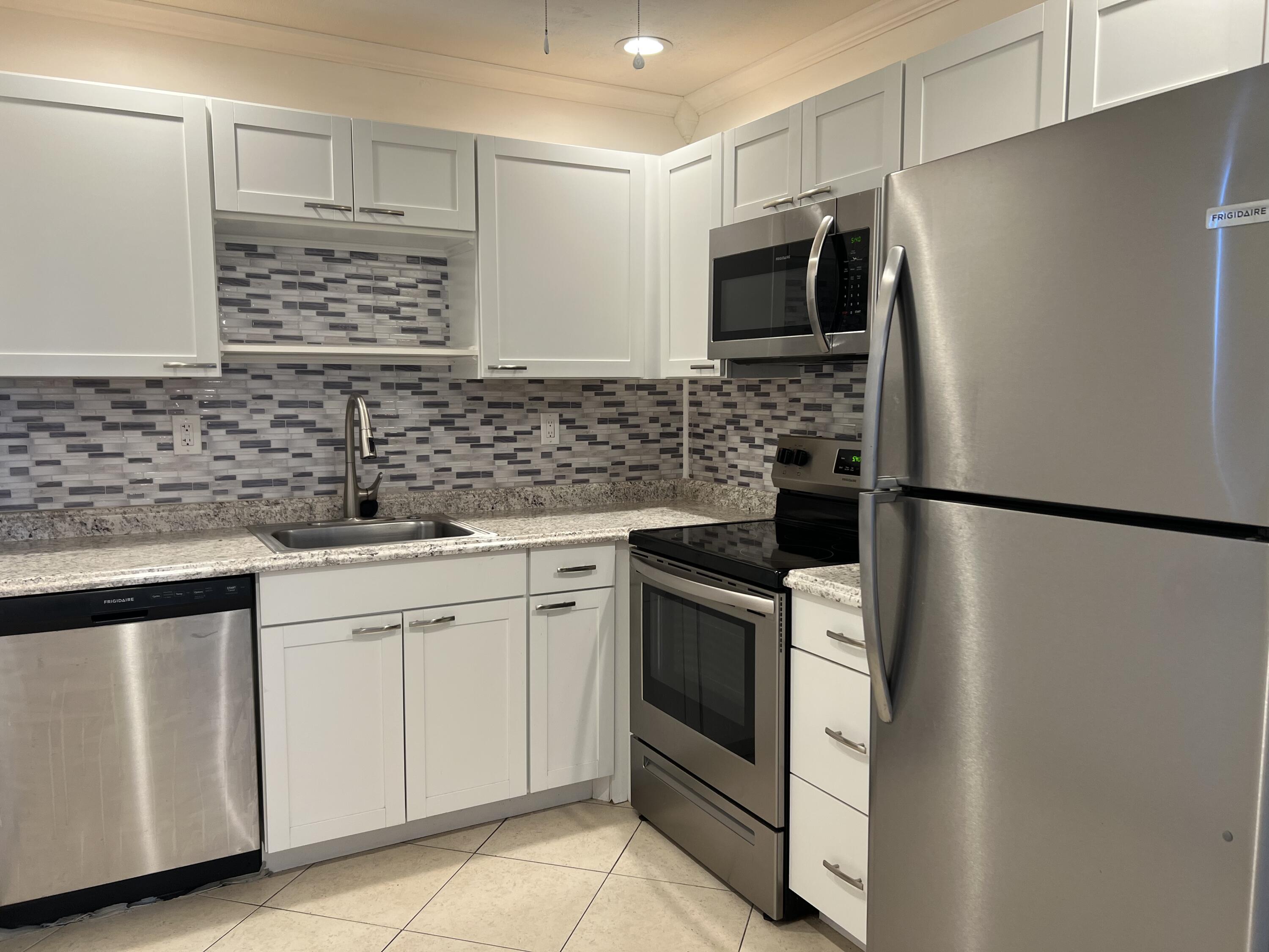 82 Normandy B Delray Beach, FL 33484 - Photo 10 of 31 a kitchen with stainless steel appliances granite countertop a refrigerator and a sink