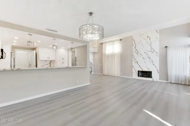 an empty room with wooden floor and kitchen view