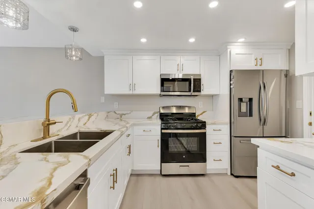 a kitchen with stainless steel appliances a stove a sink a refrigerator a microwave and cabinets