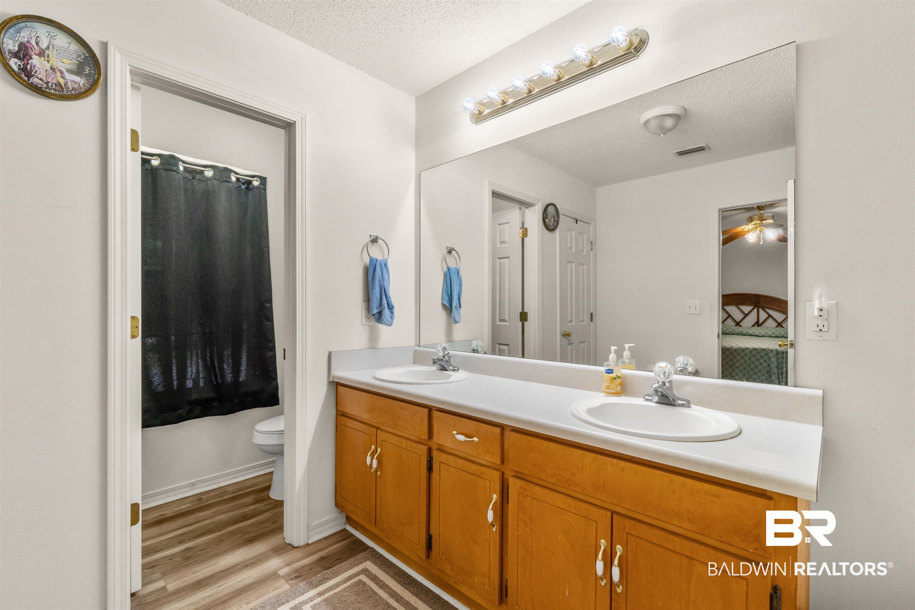 35893 Pine Road South Stapleton, AL 36578 - Photo 16 of 31 Bathroom featuring a dual vanity with wood-finish cabinetry, white countertops, and a large wall-mounted mirror