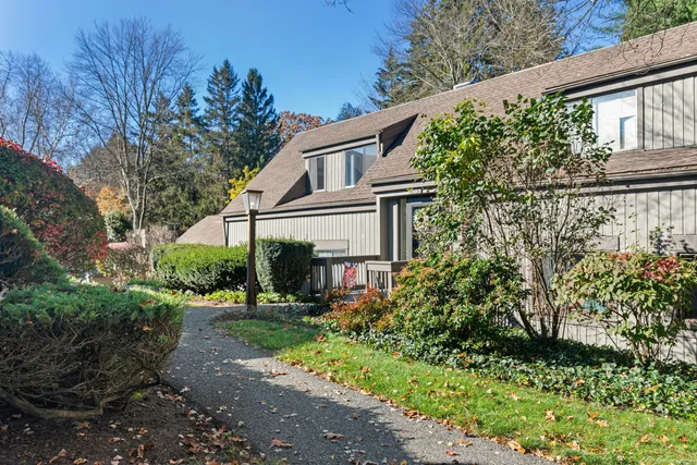 a view of a white house with a big yard and potted plants