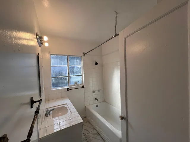 a bathroom with a tub shower vanity and a sink