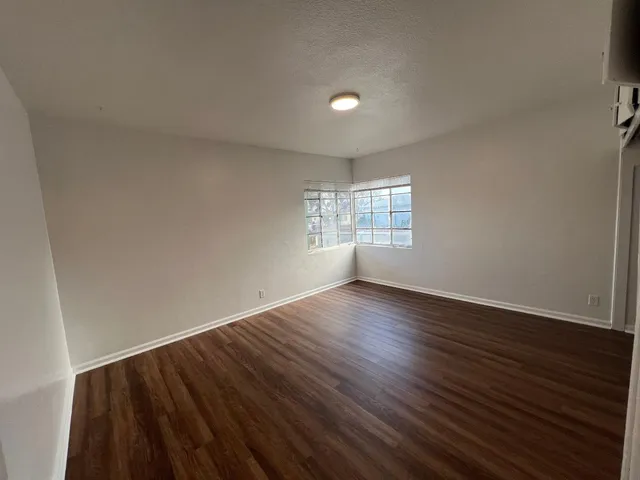 a view of an empty room with wooden floor and window