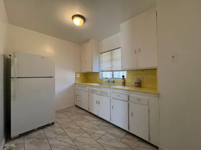an empty room with wooden floor chandelier fan and windows