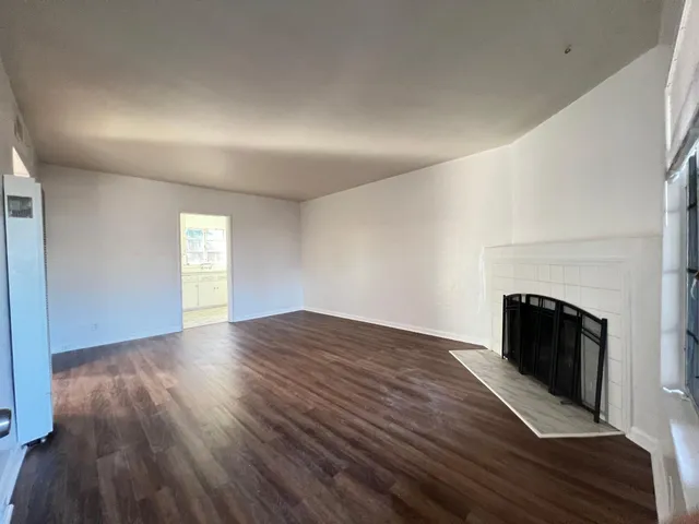 an empty room with wooden floor and fireplace