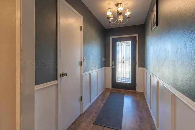 a view of a hallway with wooden floor and chandelier
