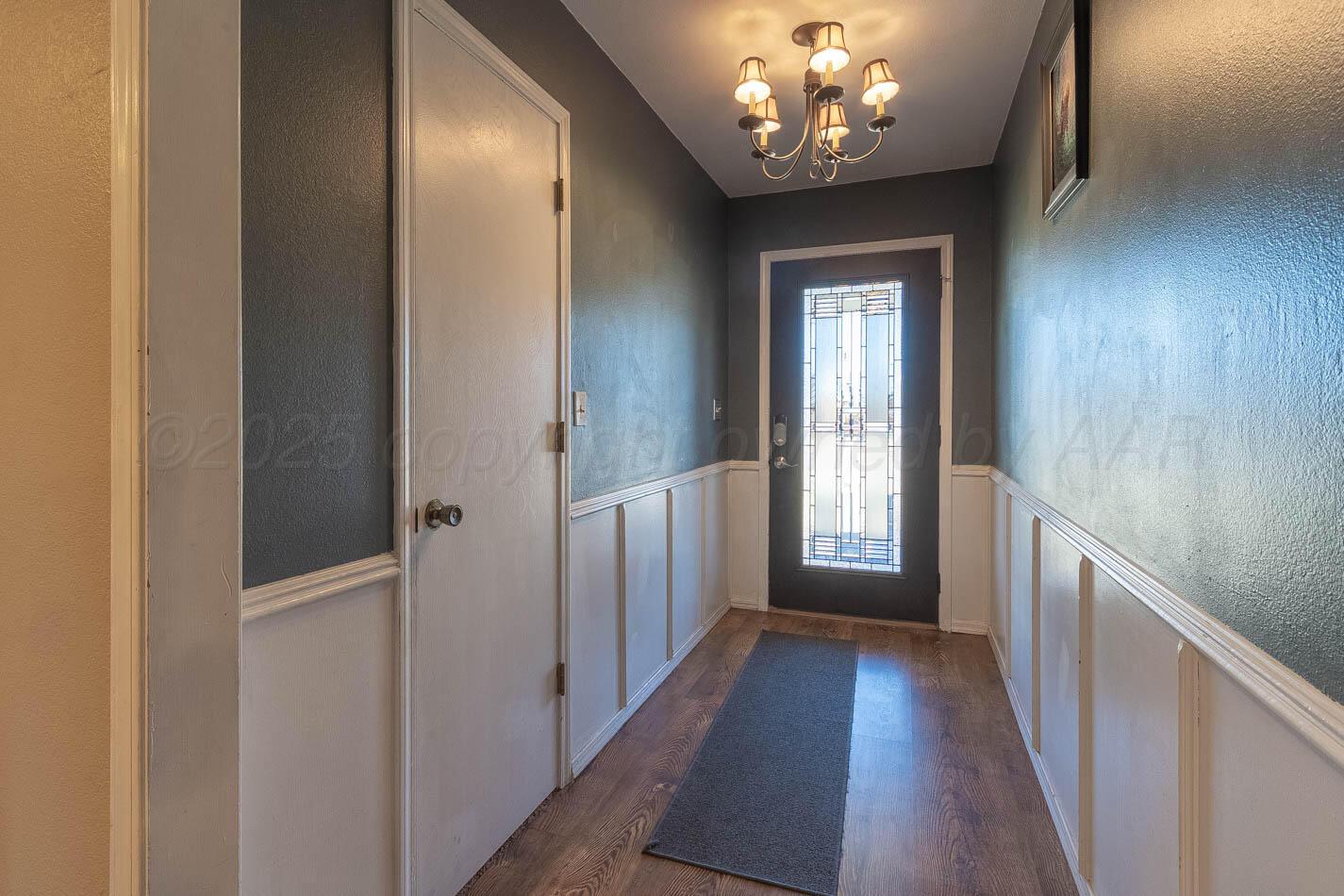 428 Overland Trail Fritch, TX 79036 - Photo 4 of 24 a view of a hallway with wooden floor and chandelier