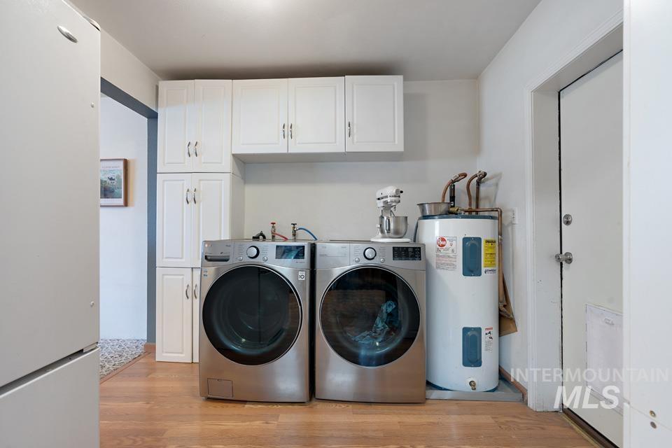 1015 East Park Street Weiser, ID 83672 - Photo 15 of 30 Laundry room with cabinet space, electric water heater, light wood-style floors, and separate washer and dryer