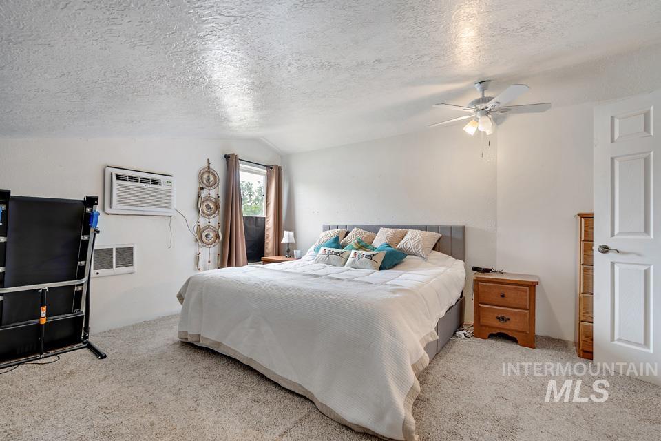 1015 East Park Street Weiser, ID 83672 - Photo 21 of 30 Carpeted bedroom featuring a textured ceiling, lofted ceiling, a wall mounted AC, and ceiling fan