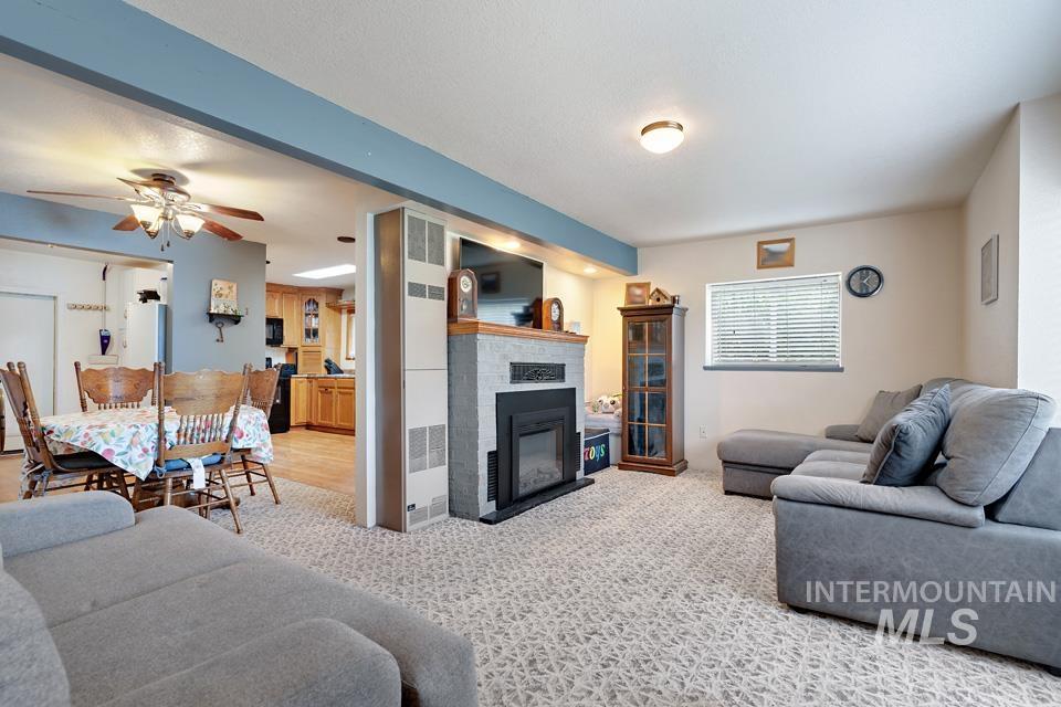 1015 East Park Street Weiser, ID 83672 - Photo 9 of 30 Living room with ceiling fan, a glass covered fireplace, and light carpet