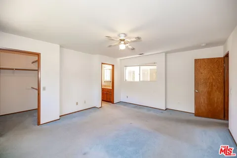 an empty room with windows and ceiling fan