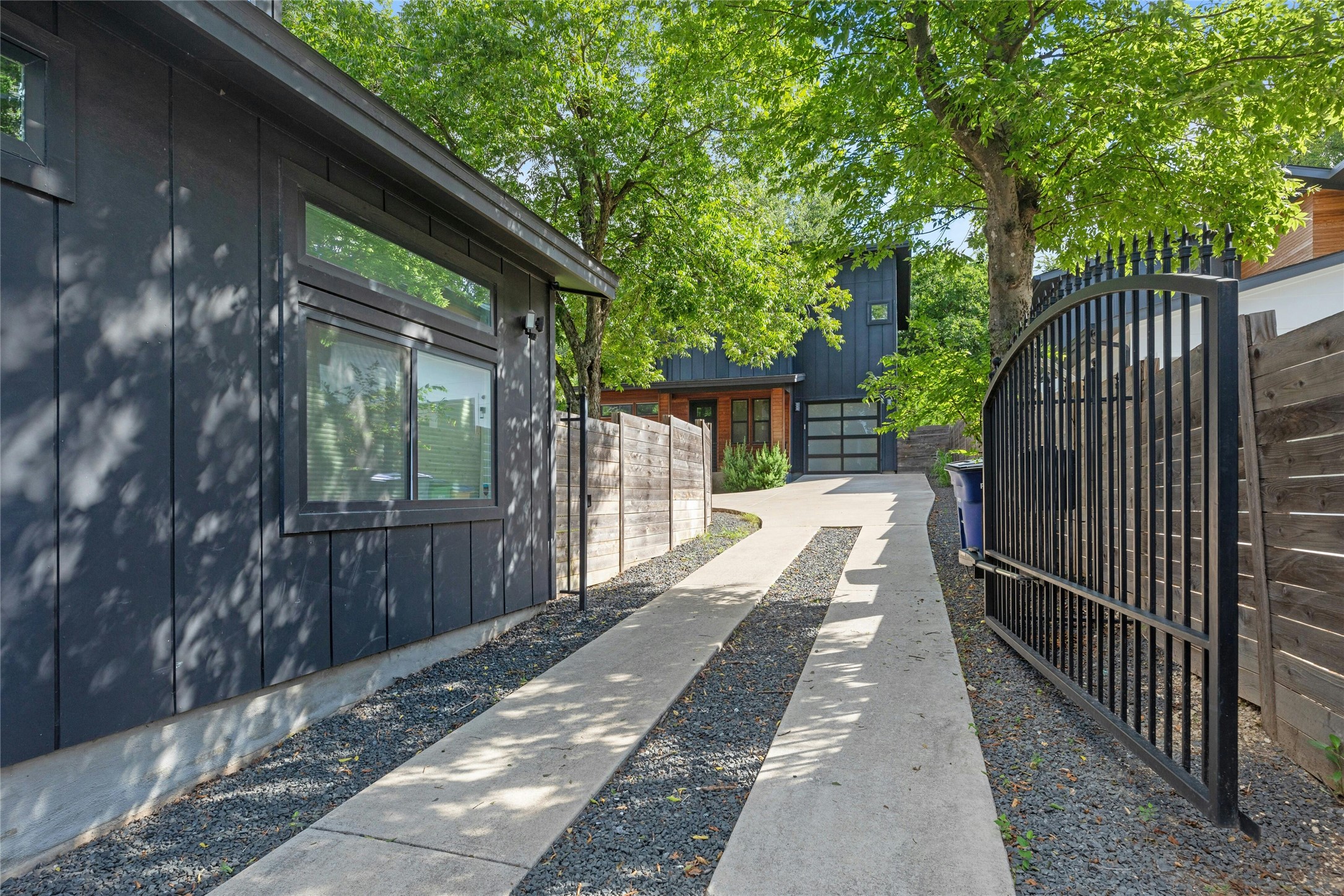 4606 Ledesma Road, Unit 2 Austin, TX 78721 - Photo 4 of 33 A private driveway with a secure gate leads to a modern home, shaded by mature trees.