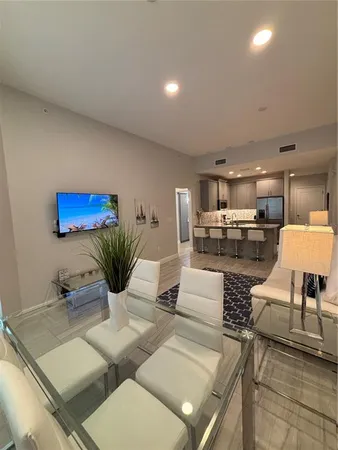 a kitchen with granite countertop a stove a sink a refrigerator and chairs