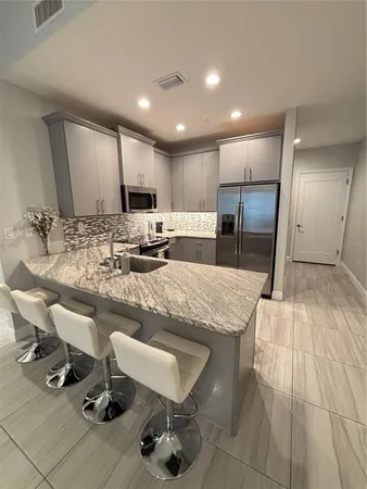 a kitchen with kitchen island a counter top space a sink stainless steel appliances and cabinets