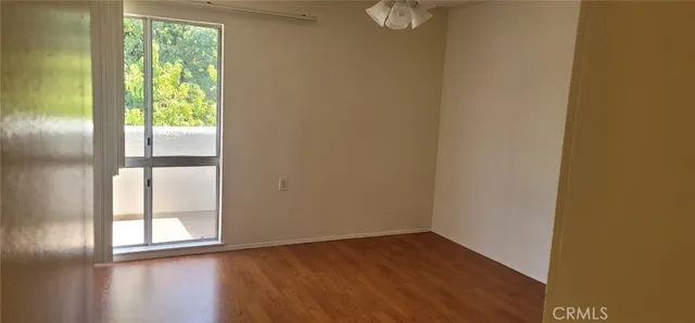 a view of empty room with wooden floor and fan