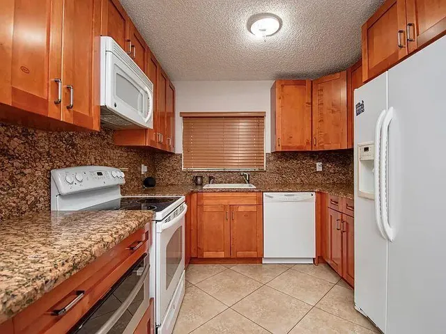 a kitchen with stainless steel appliances granite countertop a stove a sink and a refrigerator