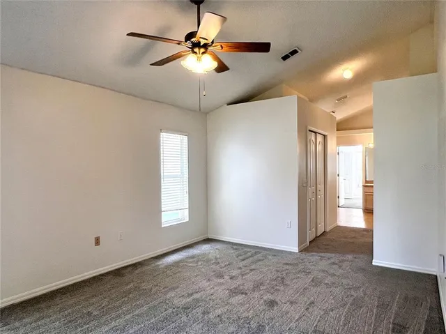 a view of an empty room and a chandelier fan